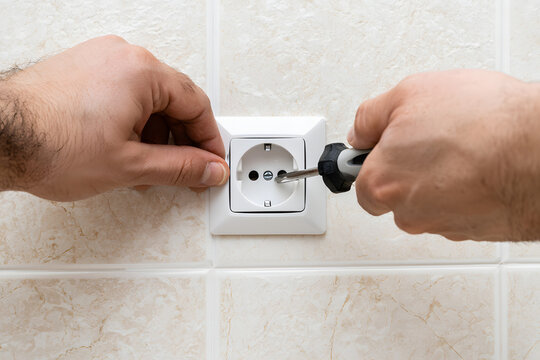 Installing a wall-mounted electrical outlet socket in the kitchen during home renovation, electrical work, and apartment repair, requiring a screwdriver for power supply connection