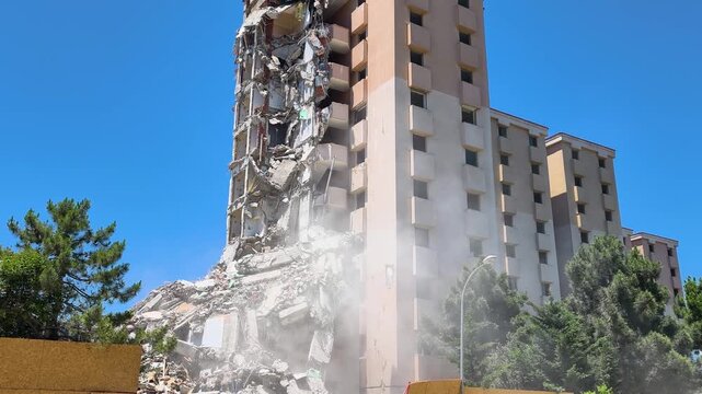 Demolition of a high-rise building takes place in a busy urban area