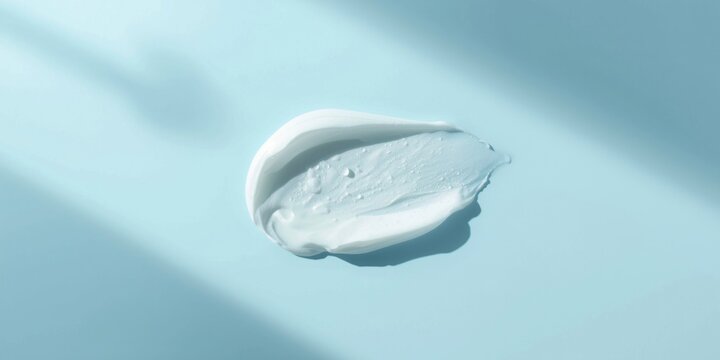 Creamy moisturizer smear on a light blue background