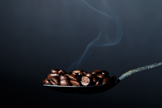 Hot Roasted Coffee Beans on Vintage Spoon with Delicate Smoke Effect
