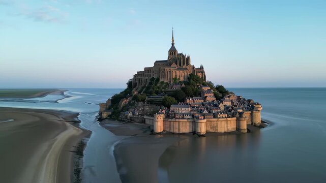 Bastille Day aerial Mont Saint-Michel island abbey, tidal flats, golden archangel spire, morning light, cinematic drone orbit, France July 14 national day landmark b-roll