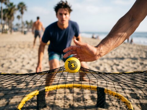 Friends playing spikeball on beach at sunset