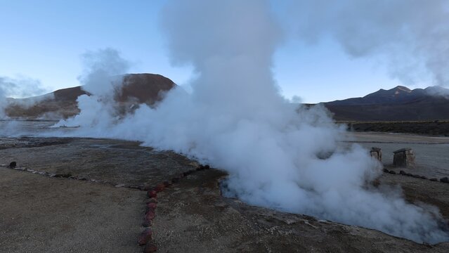 View of El Tatio geysers with rising steam plumes against a clear sky in the high altitude desert landscape of Antofagasta, Antofagasta, Chile.
