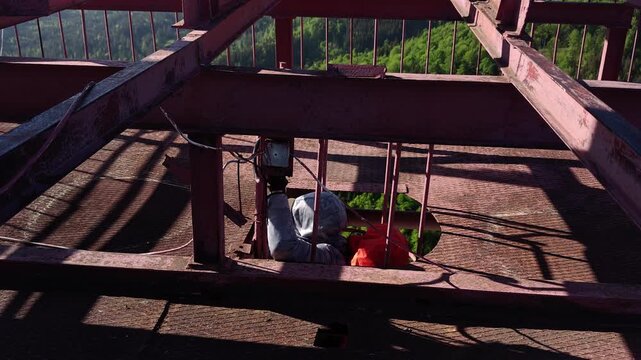 Man climbing vertical cage ladder inside 75m repurposed radar tower