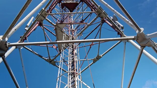 Man climbing vertical cage ladder inside 75m repurposed radar tower