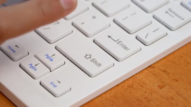 Little finger pressing Shift key on white computer keyboard closeup