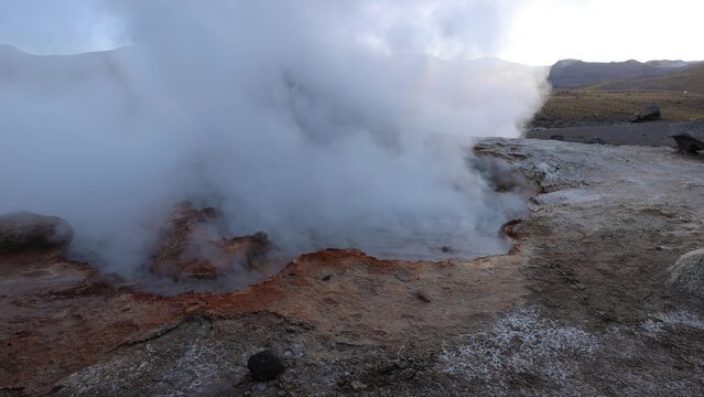 View of El Tatio geyser field with rising steam and geothermal activity over rocky volcanic terrain in Antofagasta, Antofagasta, Chile.