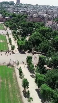 Bastille Day top-down aerial Champ de Mars Paris, Eiffel Tower foot shadow on grass, formal geometric park, bird's eye view, cinematic France July 14 drone b-roll