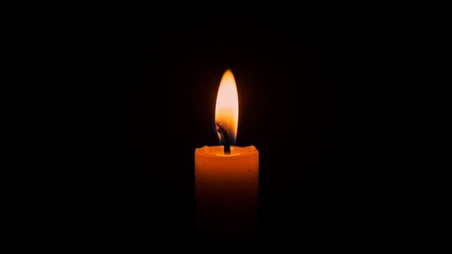 Single burning candle flame glowing in dark background for peaceful ambiance and meditation