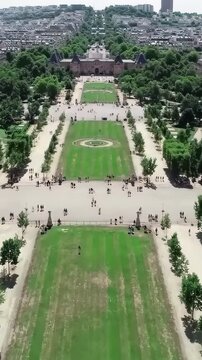 Bastille Day top-down aerial Champ de Mars Paris, Eiffel Tower foot shadow on grass, formal geometric park, bird's eye view, cinematic France July 14 drone b-roll