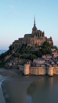 Bastille Day aerial Mont Saint-Michel island abbey, tidal flats, golden archangel spire, morning light, cinematic drone orbit, France July 14 national day landmark b-roll