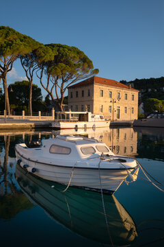 Small motorboat moored in calm waters of Jelsa harbor at sunrise