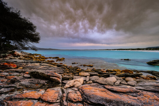 View of East Bay Camping Ground with rocky coastline, turquoise water, and dramatic stormy clouds in Manypeaks, Western Australia, Australia.