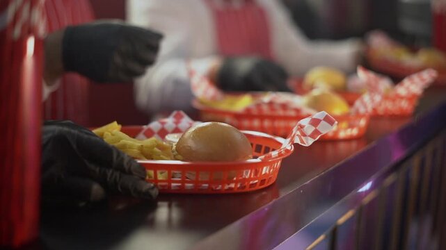 A succulent hamburger with yellow cheese and french fries served on a red checkered plastic plate
