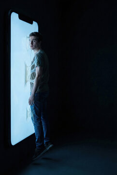 Conceptual Metaphor of a Young Man Consumed and Addicted to a Glowing Smartphone Screen