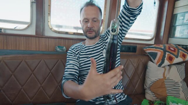 Man shows his fishing lures to the camera while sitting in the moving boat