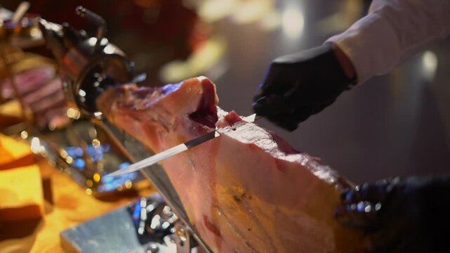 A chef cuts a leg of high-quality Iberian ham with his knife at a very elegant party