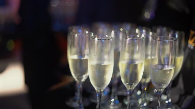 A waiter holds a tray with many champagne glasses before a toast at a gala party