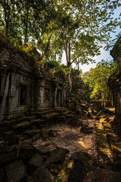 View of the ancient stone ruins of Beng Mealea temple, overgrown with trees and moss, featuring scattered stone blocks and intricate carvings in Krong Siem Reap, Siem Reap Province, Cambodia.