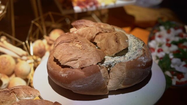 A large bread filled with a spinach dip at a snack station at a wedding party
