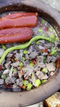 Cooking delicious meat casserole in a clay pot during a wilderness camping trip.