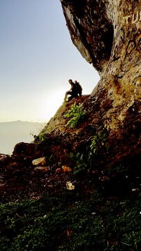 Silhouette of a man walking inside a cave and sitting to watch the sunrise