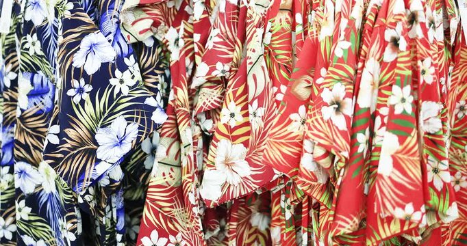 Colorful Hawaiian floral shirts hanging on a clothing rack in a retail store. Perfect for summer fashion, tropical lifestyle, travel, shopping, apparel, and retail concepts