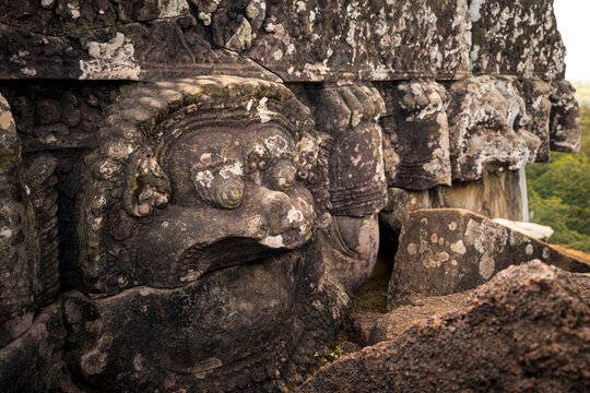View of intricate stone carvings of mythical figures on the ancient temple walls in Krong Siem Reap, Siem Reap Province, Cambodia.