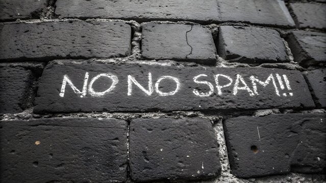 Chalk writing on a dark brick wall reading no spam with two exclamation marks in white texture