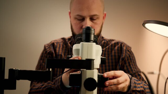 Technician inspecting electronic components under stereo microscope