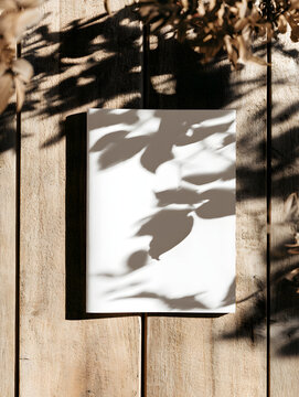 A natural leaf-shadowed, warmly lit wooden surface mockup for a blank white brochure or magazine