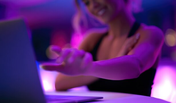 Webcam model posing online chat for subscribers only fans. Sexy girl Live Streaming from laptop in pink purple neon light room. Creation of private digital content theme. Woman web cam attracts client