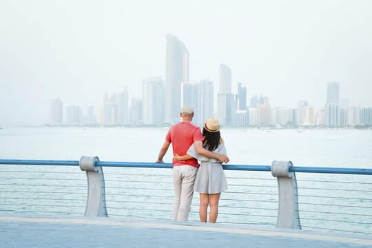 Caucasian tourist romantic couple stand together enjoy skyline panorama on scenic viewpoint in Abu dhabi. Visit travel sightseeing UAE concept