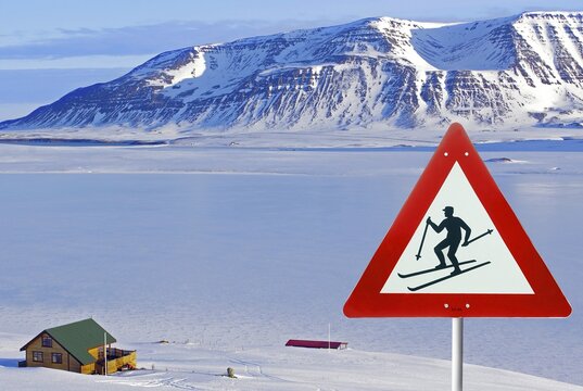 Traffic sign warns of skiers, wintry landscape and hut, composition, Iceland