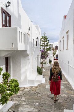 Young woman with red skirt in the alleys of Ano Mera, Cycladic white houses, Ano Mera, Mykonos, Cyclades, Greece