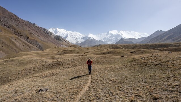 Mountaineers in the Achik Tash valley, in the background glaciated and snow-covered mountain peak Lenin Peak and Peak of the XIX Party Congress of the CPSU, Trans Alay Mountains, Pamir Mountains, Osh Province, Kyrgyzstan
