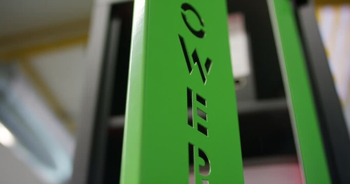 Close up view of cut out text letters on a green vertical metal beam panel of a storage machine
