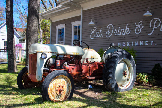 Old Rustic Dilapidated Tractor Vehicle in Front Lawn of Restaurant Building With Wall Mural in Mckinney, Texas