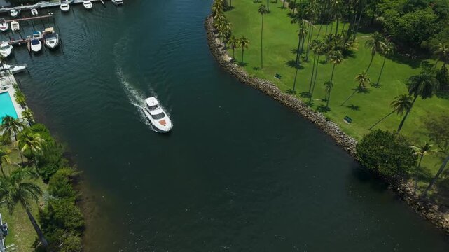 Top down aerial view of yachts cruising near a green waterfront park