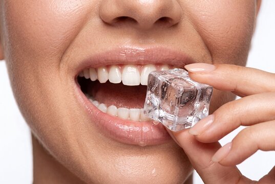 Close up of woman eating ice cube for teeth health and hydration