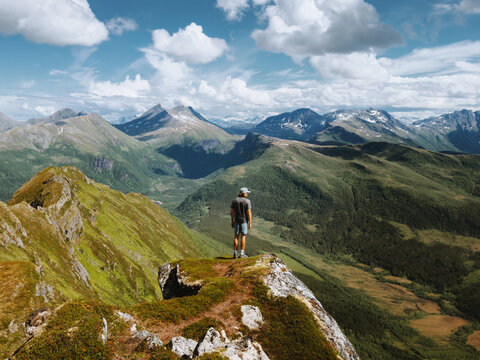 Man travel solo in Norway standing alone on summit cliff edge climbing mountains healthy lifestyle active adventure summer vacations extreme tour in the great outdoors, freedom harmony with nature