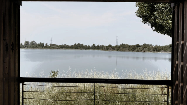 Scenic view of a calm lake and distant trees framed through a dark rectangular open structure