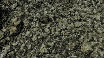 Fototapeta premium Clear shallow water rippling over a rocky riverbed covered in pebbles and stones