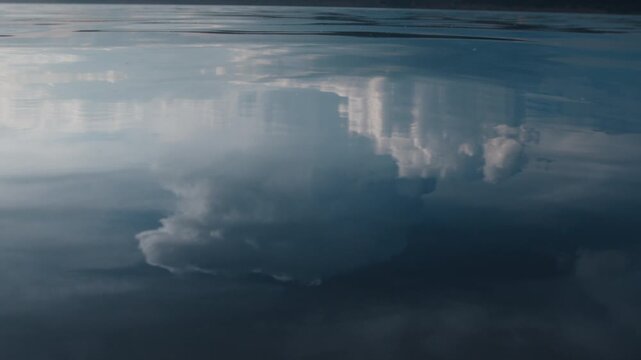 Glassy surface of the river with reflection of the cumulonimbus clouds