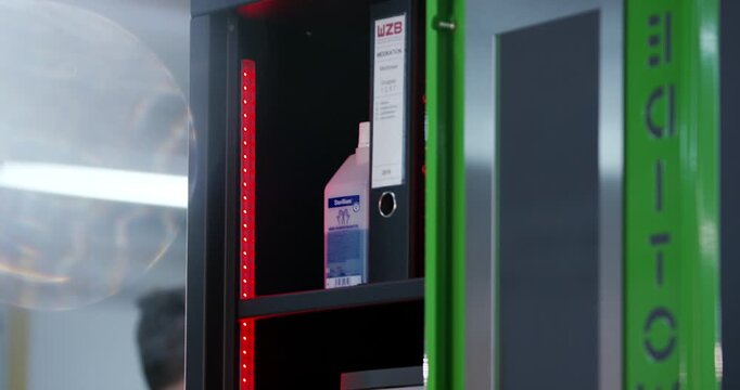 Close up view of a plastic container box and rolled labels inside an open safe cabinet shelf