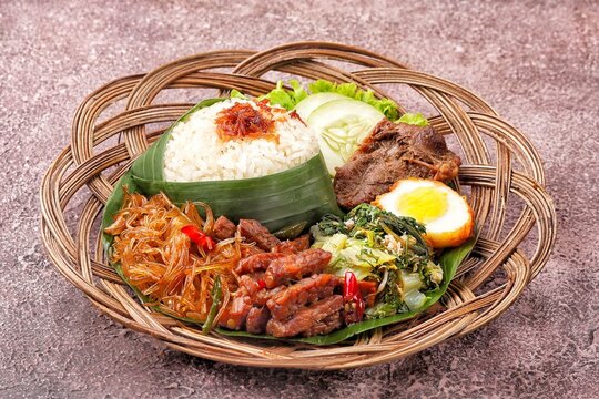 Nasi Berkat Wonogiri, a classic Indonesian ceremonial meal from Wonogiri, Central Java, featuring steamed rice with assorted side dishes such as fried chicken or beef, tempeh, vegetables, sambal, nood