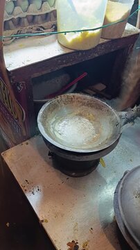 A street food vendor processes Kerak Telor (a traditional Jakarta spicy omelette made from glutinous rice and egg) in a small wok over a traditional charcoal brazier stove