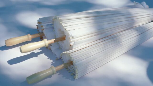 Stylish white vintage umbrellas provide shade from the hot, bright sun on a sunny summer day. Wedding ceremony for the bride and groom.