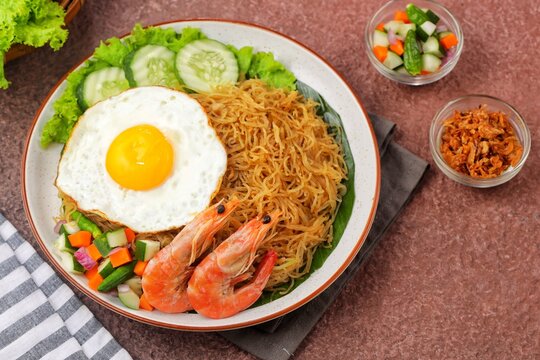 Bihun goreng, bee hoon goreng or mee hoon goreng refers to a dish of fried noodles cooked with rice vermicelli. Served with vegetables, sunny side up egg, and shrimp.
