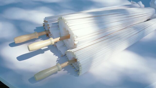 Stylish white vintage umbrellas provide shade from the hot, bright sun on a sunny summer day. Wedding ceremony for the bride and groom.